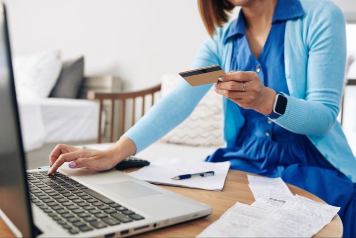 Woman wearing blue dress paying bills online on her laptop