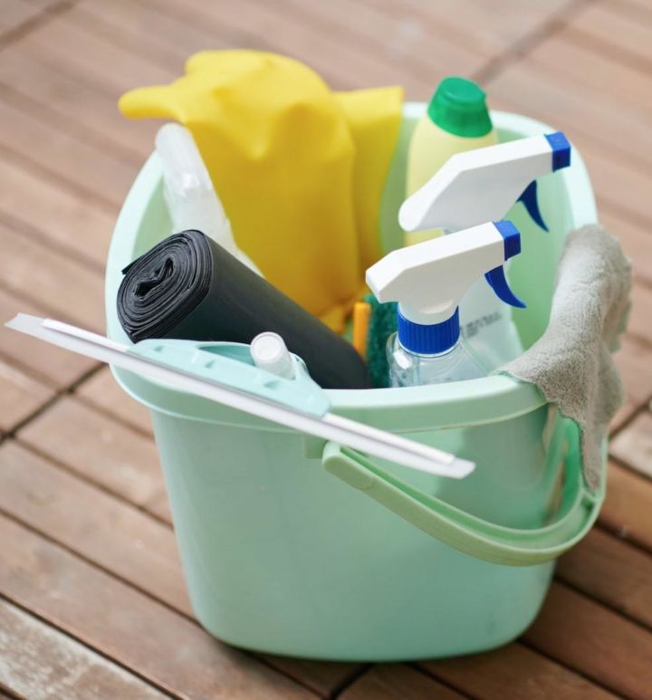 Mint colored plastic bucket with various cleaning supplies in it